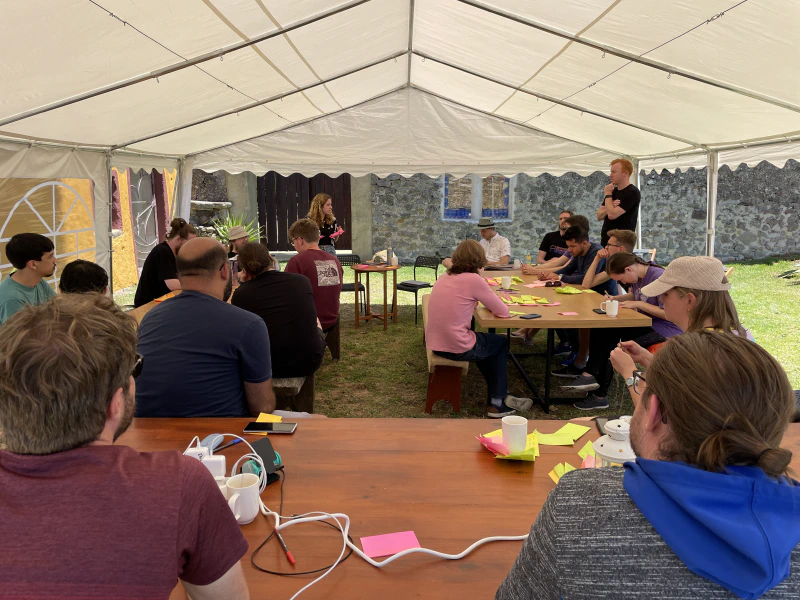 Caroline (standing left) is discussing her retro sticky notes as Brad (standing right) looks on.